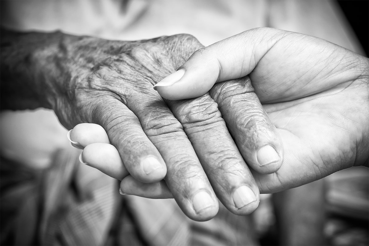 A woman's hand holding a man's hand that's living with Parkinson's Disease