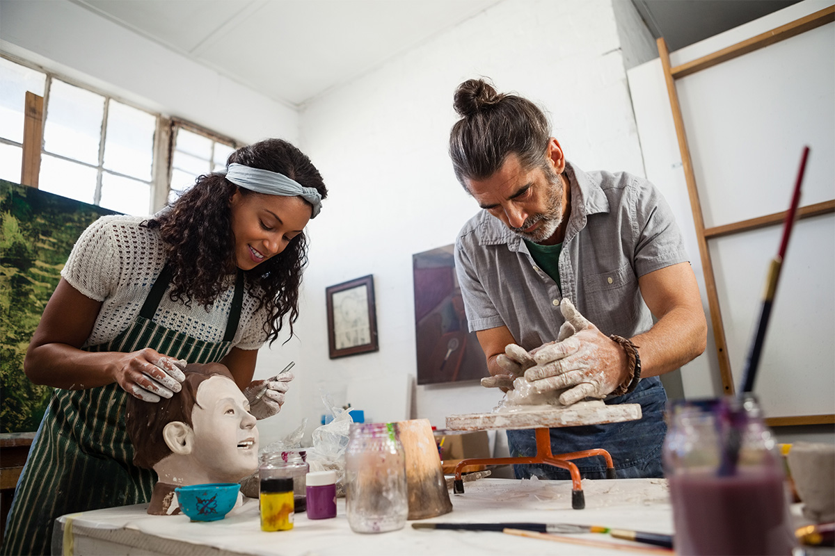 Two artists with Parkinson's sculpting in a class