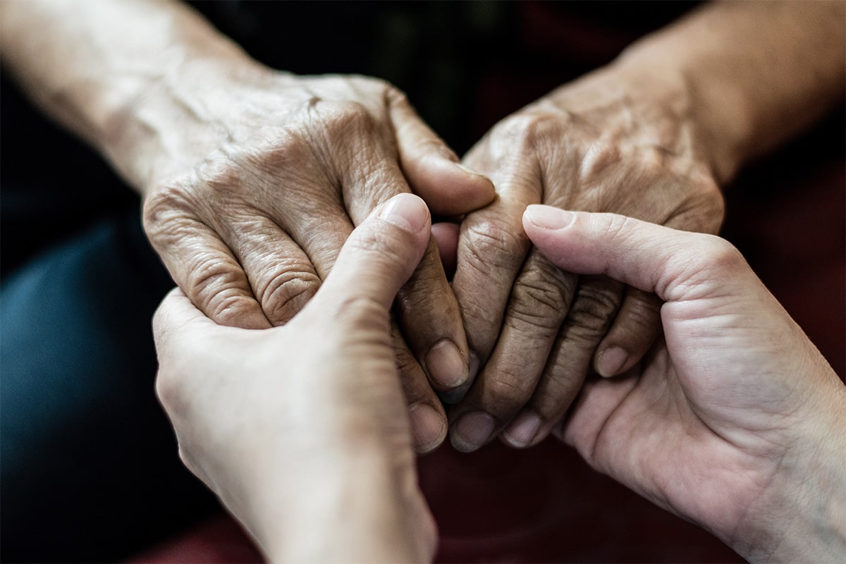 Two hand embracing as one struggles with Parkinson's disease