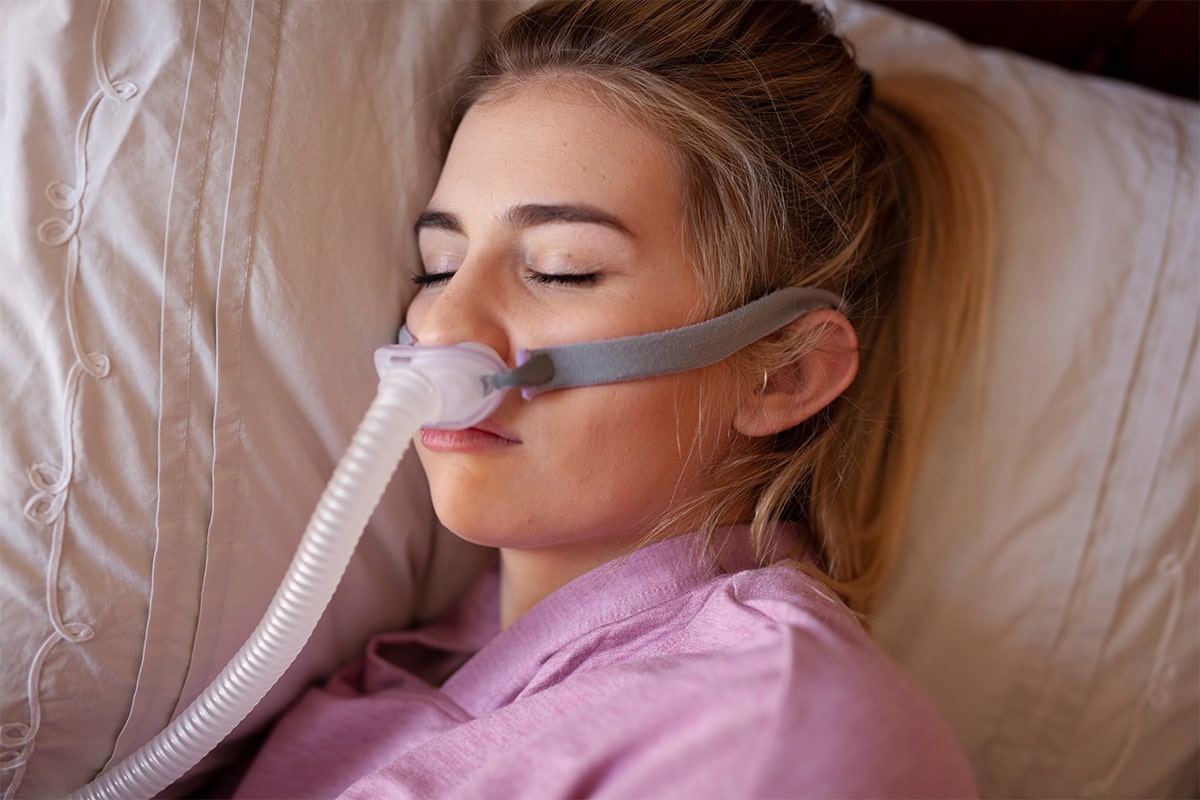 Woman struggling with Parkinson's disease sleeping in bed with a sleep apnea machine