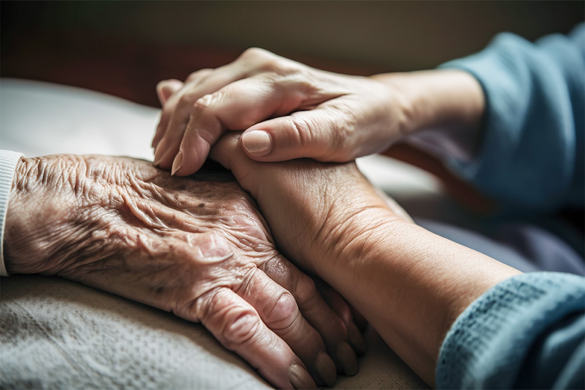 An elderly hand embracing a younger hand as they discuss Parkinson's diagnosis